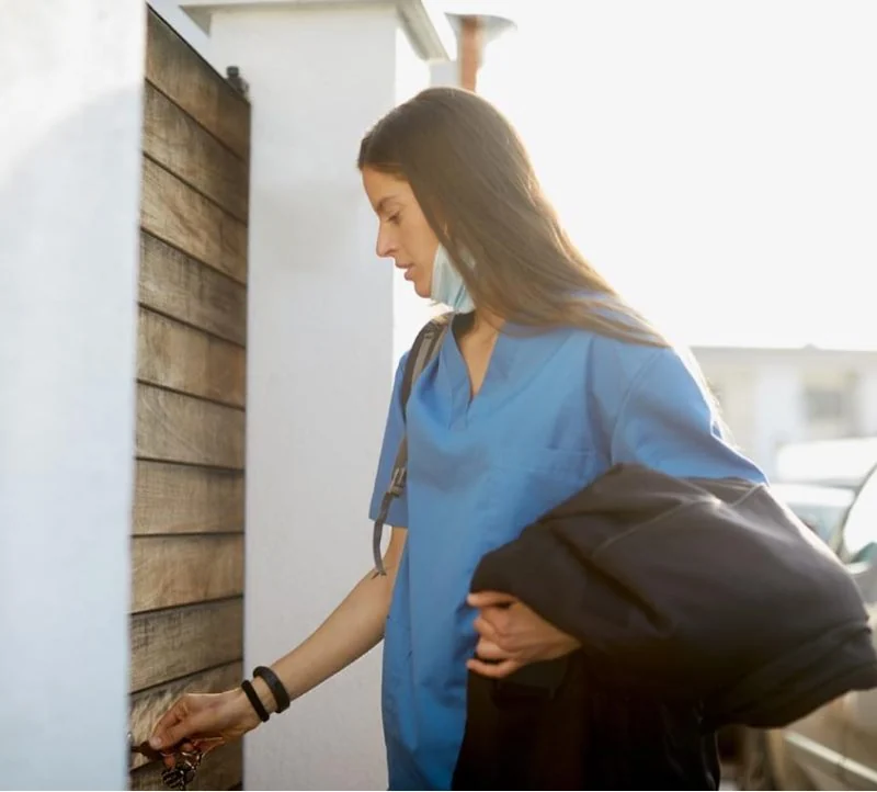 A nurse arriving home with a work bag