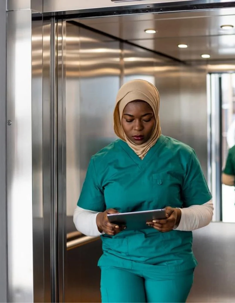 A nurse using a tablet in a hospital elevator